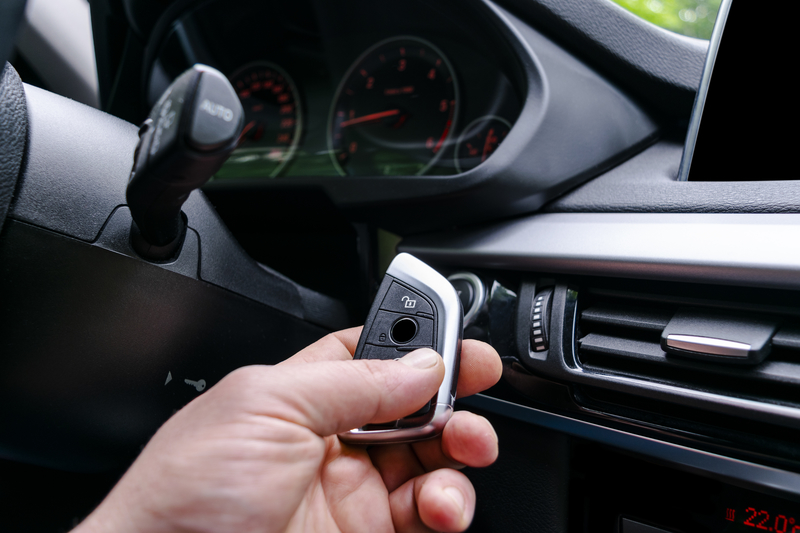 Closeup inside vehicle of man hand holding wireless key ignition inside vehicle